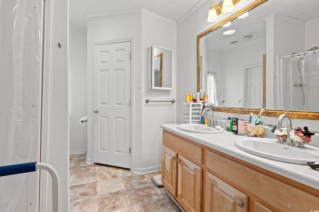 Full bath with double vanity, crown molding, a shower with curtain, and a textured ceiling | Image 14