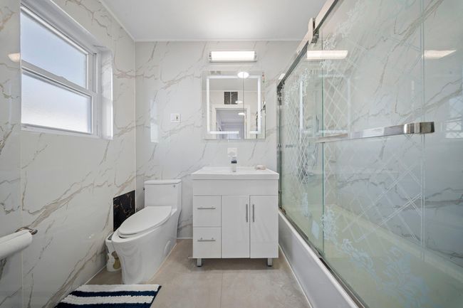 Bathroom featuring vanity, toilet, marble finish floor, and bath / shower combo with glass door | Image 15
