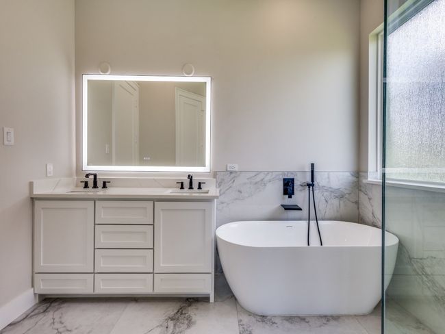 Bathroom featuring marble finish flooring, tile walls, double vanity, a freestanding bath, and a wainscoted wall | Image 34