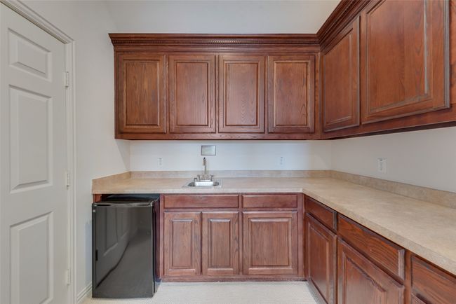 Kitchen featuring light countertops, dishwashing machine, and brown cabinets | Image 14