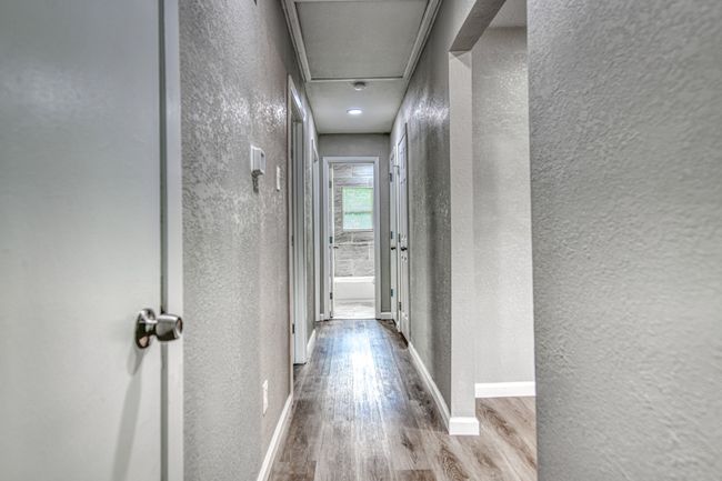 Hallway featuring a textured wall, wood finished floors, and attic access | Image 16