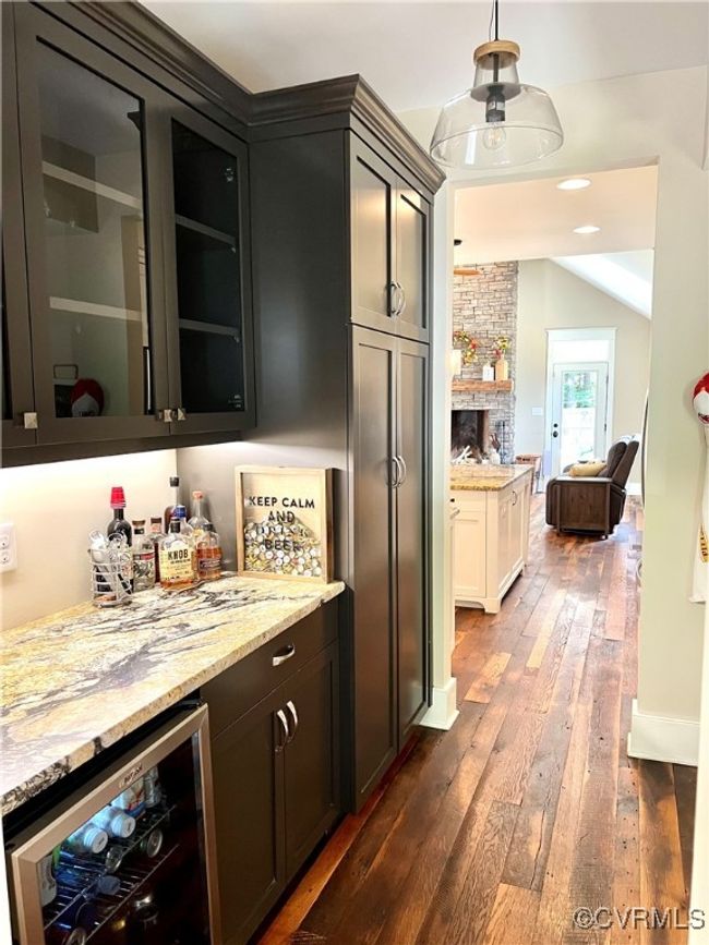 Indoor dry bar featuring wine cooler, reclaimed oak wood finished floors, hanging light fixtures, and vaulted ceiling | Image 8