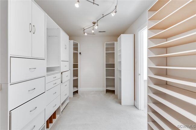 Opposite view of primary walk-in closet featuring custom built shelving | Image 32