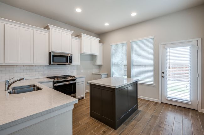 Kitchen featuring white cabinets, appliances with stainless steel finishes, light hardwood / wood-style flooring, and a kitchen island | Image 12