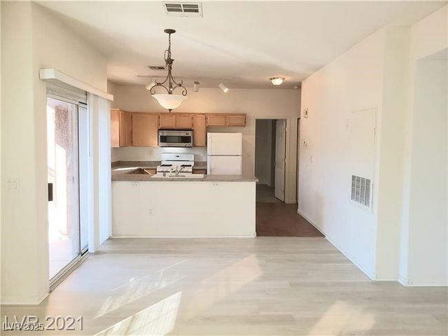 Kitchen with white appliances, pendant lighting, a peninsula, light wood-style flooring, and light brown cabinetry | Image 6