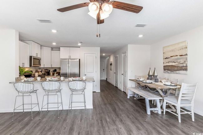 Kitchen with stainless steel appliances, a peninsula, dark wood-type flooring, recessed lighting, and white cabinets | Image 5