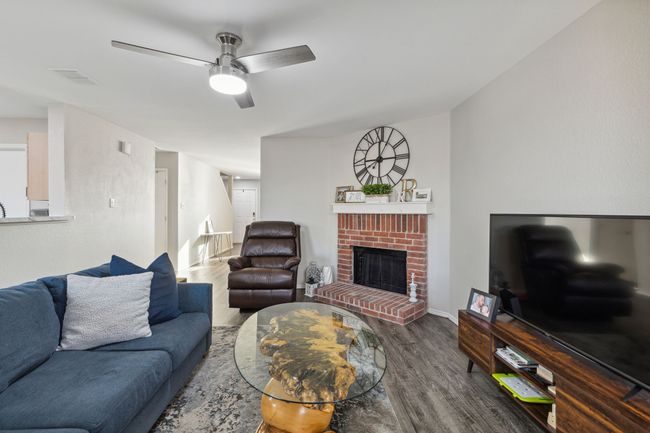 Living area with wood finished floors, a ceiling fan, and a fireplace | Image 12
