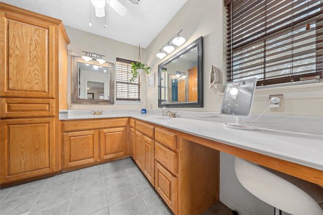 Bathroom with a ceiling fan, tile patterned floors, a textured ceiling, a sink, and double vanity | Image 20