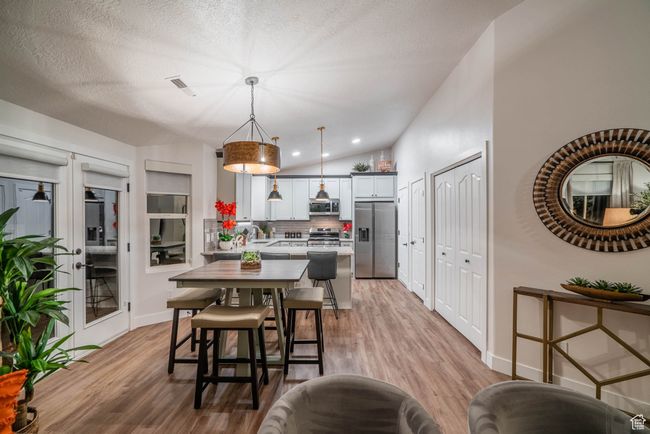Kitchen with decorative light fixtures, lofted ceiling, backsplash, appliances with stainless steel finishes, and a textured ceiling | Image 6