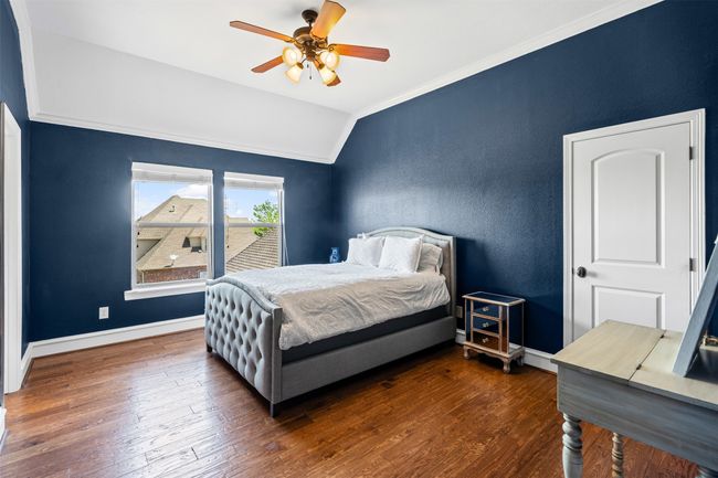 Bedroom featuring baseboards, crown molding, a ceiling fan, lofted ceiling, and wood finished floors | Image 31