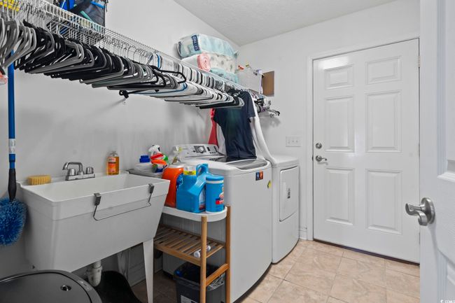 Laundry room featuring independent washer and dryer, light tile patterned floors, and a textured ceiling | Image 26