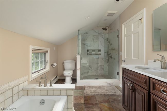 Full bathroom featuring a baseboard radiator, vaulted ceiling, separate shower and tub, vanity, and toilet | Image 40