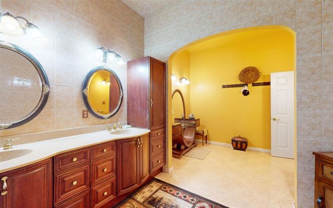 Bathroom with tile walls, double vanity, baseboards, and tile patterned floors | Image 46