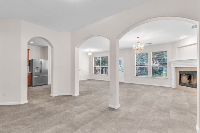 Unfurnished living room featuring arched walkways, a tiled fireplace, a chandelier, and recessed lighting | Image 6