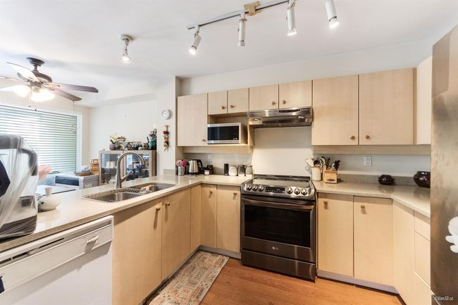 Kitchen featuring stainless steel appliances, under cabinet range hood, a sink, and light countertops | Image 7