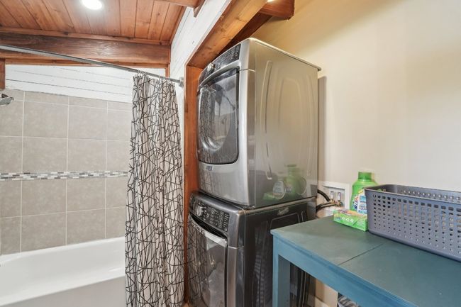 Laundry room featuring stacked washer / drying machine and wood ceiling | Image 21