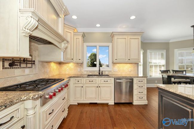 Wood flooring, wood cabinetry, kitchen island with bar seating, recessed lighting | Image 14