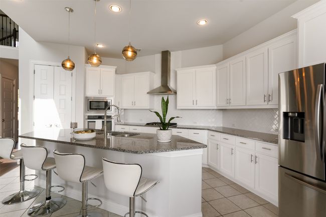 Kitchen with backsplash, wall chimney exhaust hood, appliances with stainless steel finishes, and light tile patterned flooring | Image 15
