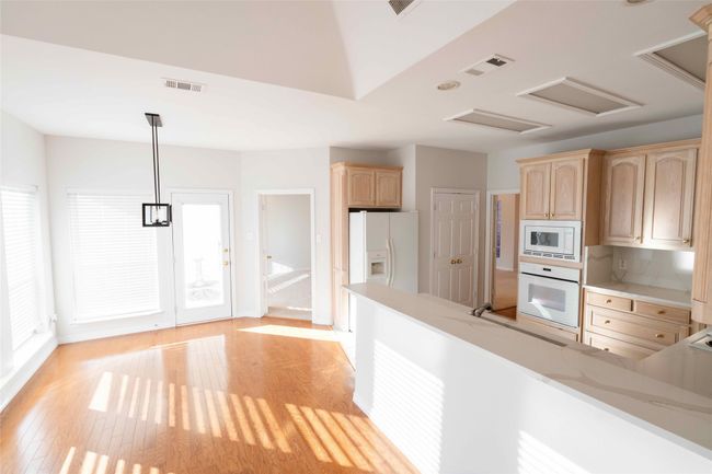 Kitchen with white appliances, light brown cabinetry, light countertops, and light wood-style floors | Image 14