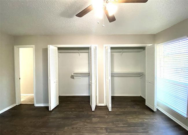 8836 Bedroom with dark wood-style floors, ceiling fan, a textured ceiling, and multiple closets | Image 29