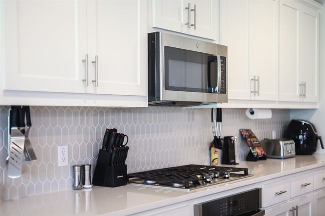 Kitchen with appliances with stainless steel finishes, light countertops, tasteful backsplash, and white cabinetry | Image 11