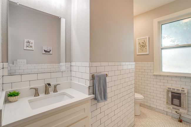 Half bathroom featuring heating unit, tile walls, vanity, wainscoting, and tile patterned floors | Image 34
