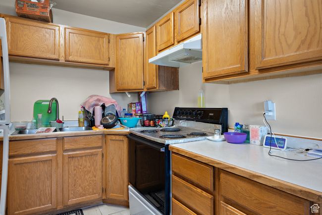 Kitchen featuring electric stove, under cabinet range hood, light countertops, and light tile patterned floors | Image 14