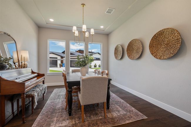 Wood floors continue into this cozy dining room with beautiful chandelier and 3 large windows. | Image 17