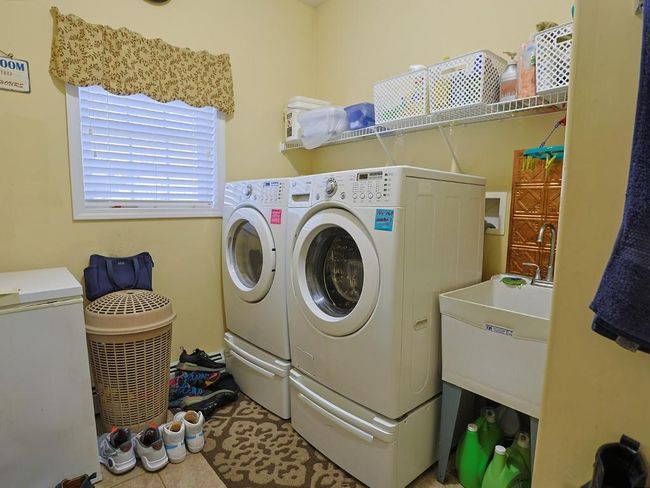 Washroom with washing machine and clothes dryer, a sink, laundry area, and tile patterned floors | Image 21