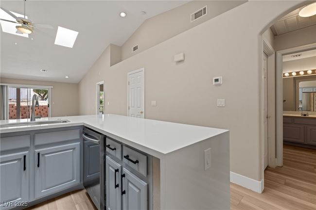 Kitchen featuring gray cabinets, light wood finished floors, recessed lighting, vaulted ceiling, and a skylight | Image 13