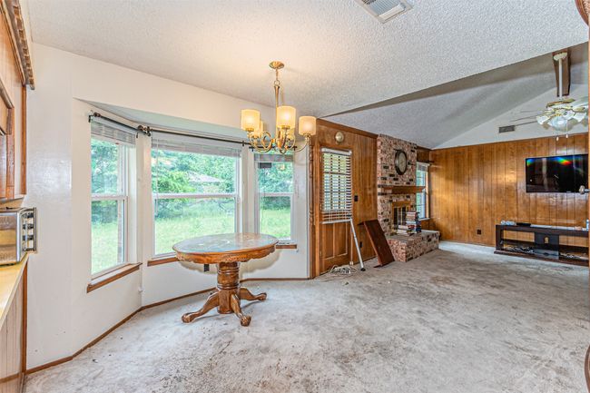 Carpeted dining room with wood walls, a textured ceiling, visible vents, and a healthy amount of sunlight | Image 24