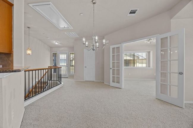 Empty room with light carpet, visible vents, baseboards, vaulted ceiling, and french doors | Image 23