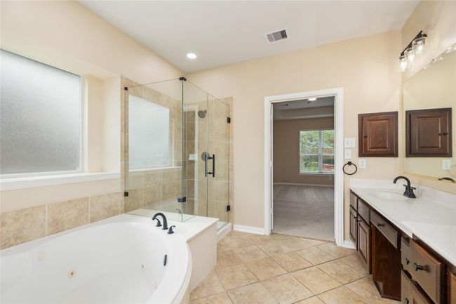 The bathroom showcases elegant tile flooring and custom wood cabinetry, providing ample and stylish storage. | Image 22