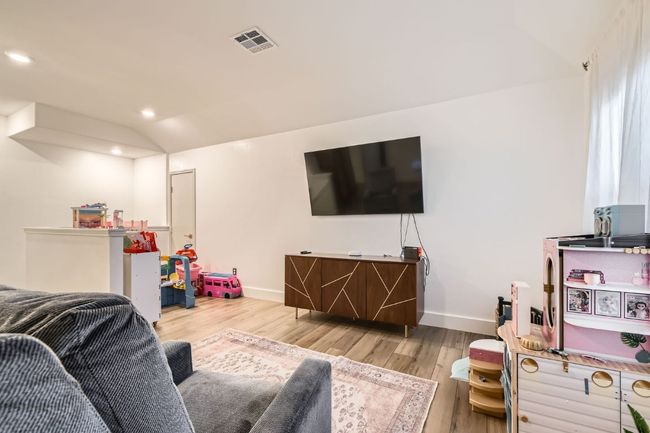Living room with wood finished floors, vaulted ceiling, and recessed lighting | Image 25