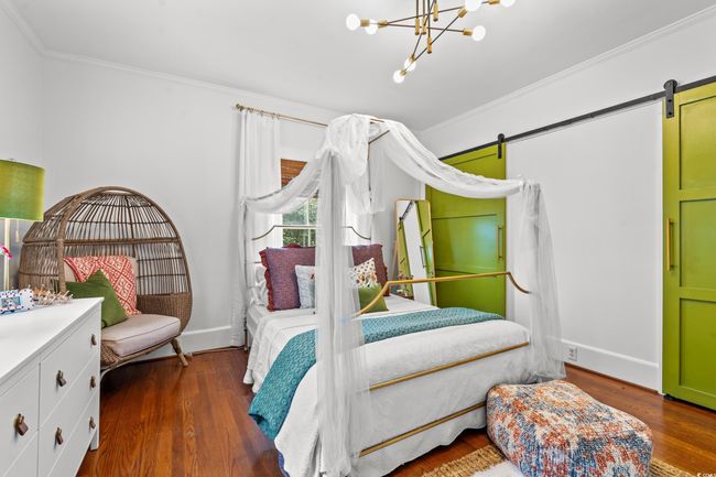 Bedroom with a barn door, crown molding, wood finished floors, and a chandelier | Image 19