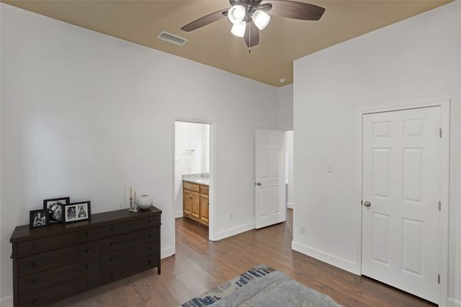 Bedroom with dark wood-type flooring, ensuite bathroom, and ceiling fan | Image 23