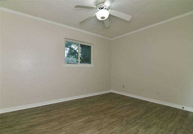 Unfurnished room with dark wood-style flooring, baseboards, ornamental molding, and ceiling fan | Image 25