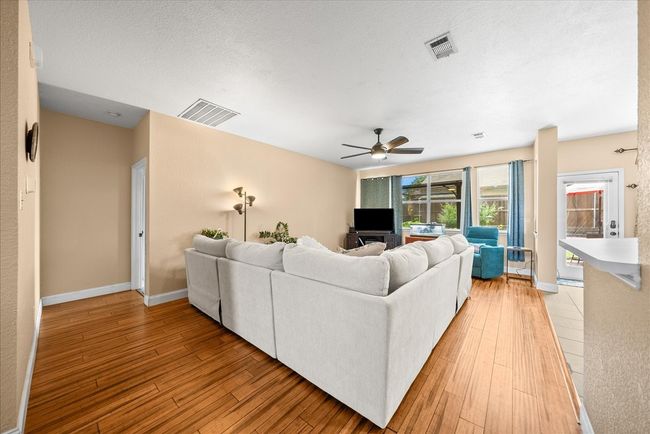Living room with ceiling fan, light wood-style floors, and baseboards | Image 14