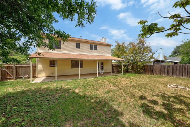 Back of property with a fenced backyard, a patio area, a lawn, and a chimney | Image 25