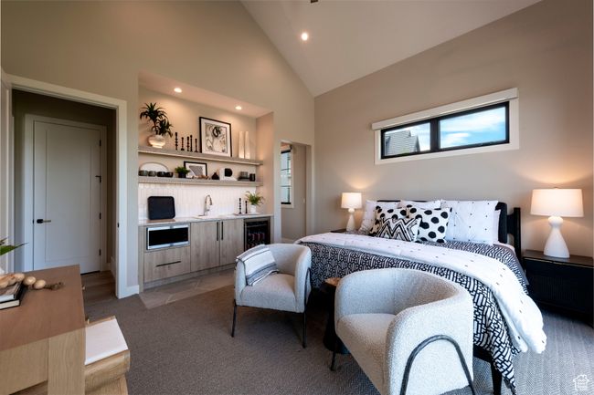 Bedroom featuring beverage cooler, bar with sink, light colored carpet, recessed lighting, and high vaulted ceiling | Image 35