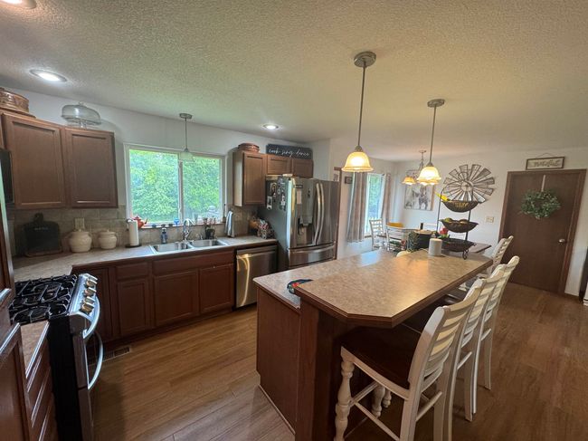 Kitchen featuring appliances with stainless steel finishes, a sink, a textured ceiling, dark wood finished floors, and decorative backsplash | Image 11