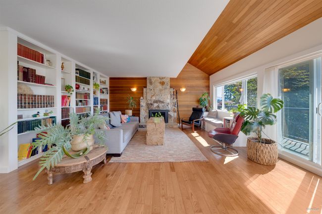 Living area featuring a fireplace, wood walls, built in shelves, hardwood / wood-style floors, and vaulted ceiling | Image 15