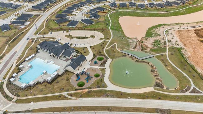 Next to the pool with the gradual depth entrance is another playground, offering a perfect spot for children to enjoy outdoor play while parents can relax nearby. The entire area is beautifully surrounded by a serene lake, adding to the peaceful and scenic atmosphere. The lake enhances the sense of tranquility, providing a stunning backdrop for both the playground and the pool, creating a serene, family-friendly environment where everyone can enjoy both water activities and outdoor fun. | Image 26
