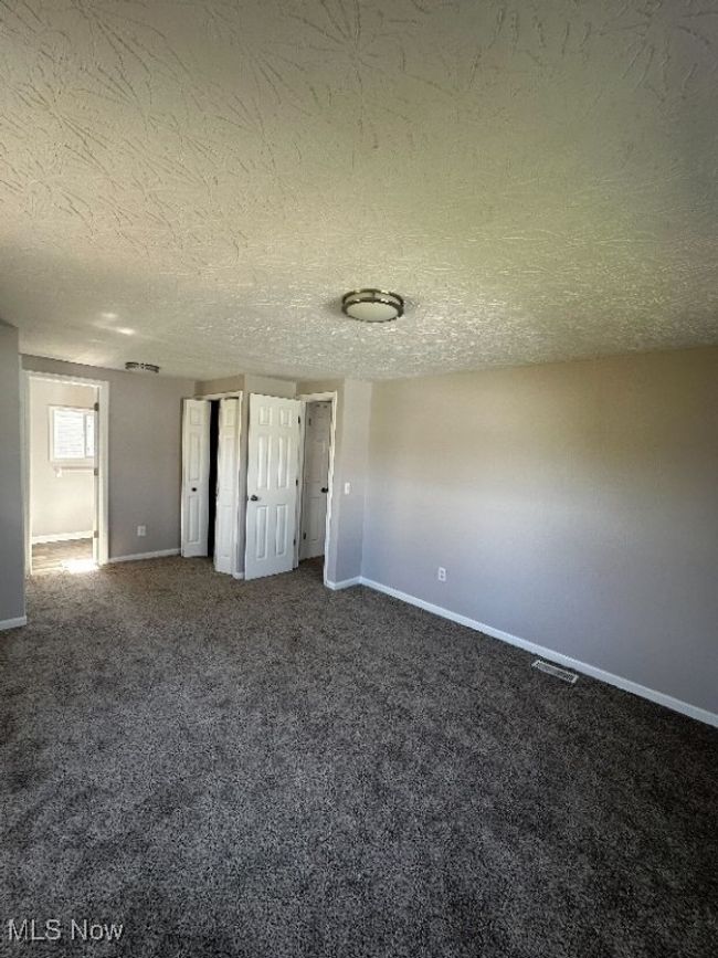 Unfurnished bedroom featuring carpet and a textured ceiling | Image 6
