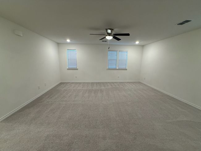Carpeted empty room featuring a ceiling fan, baseboards, and plenty of natural light | Image 31