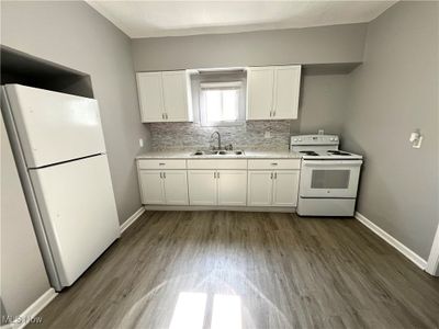 Kitchen featuring white appliances, sink, white cabinets, and hardwood / wood-style floors | Image 3