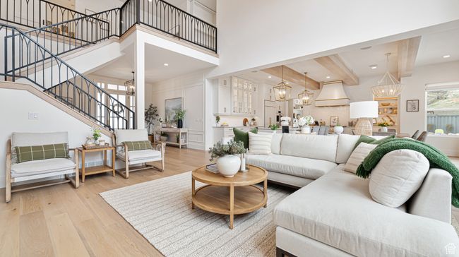 Living room with stairway, light wood finished floors, a towering ceiling, an inviting chandelier, and beamed ceiling | Image 19