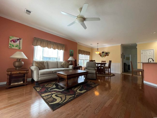 Living Room is Sundrenched with Natural Sunlight, Crown Molding, Upgraded Ceiling Fan, Hardwood Flooring. | Image 9