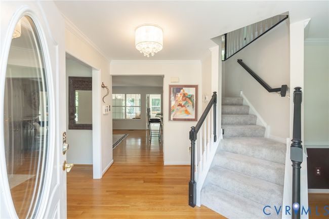 Entryway featuring light wood finished floors, ornamental molding, a chandelier, and stairway | Image 4