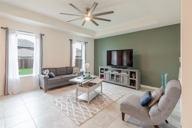 Living area featuring a ceiling fan, baseboards, a tray ceiling, and light tile patterned floors | Image 16